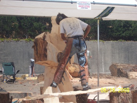 Sculptor of wood with chain saw working on large piece.